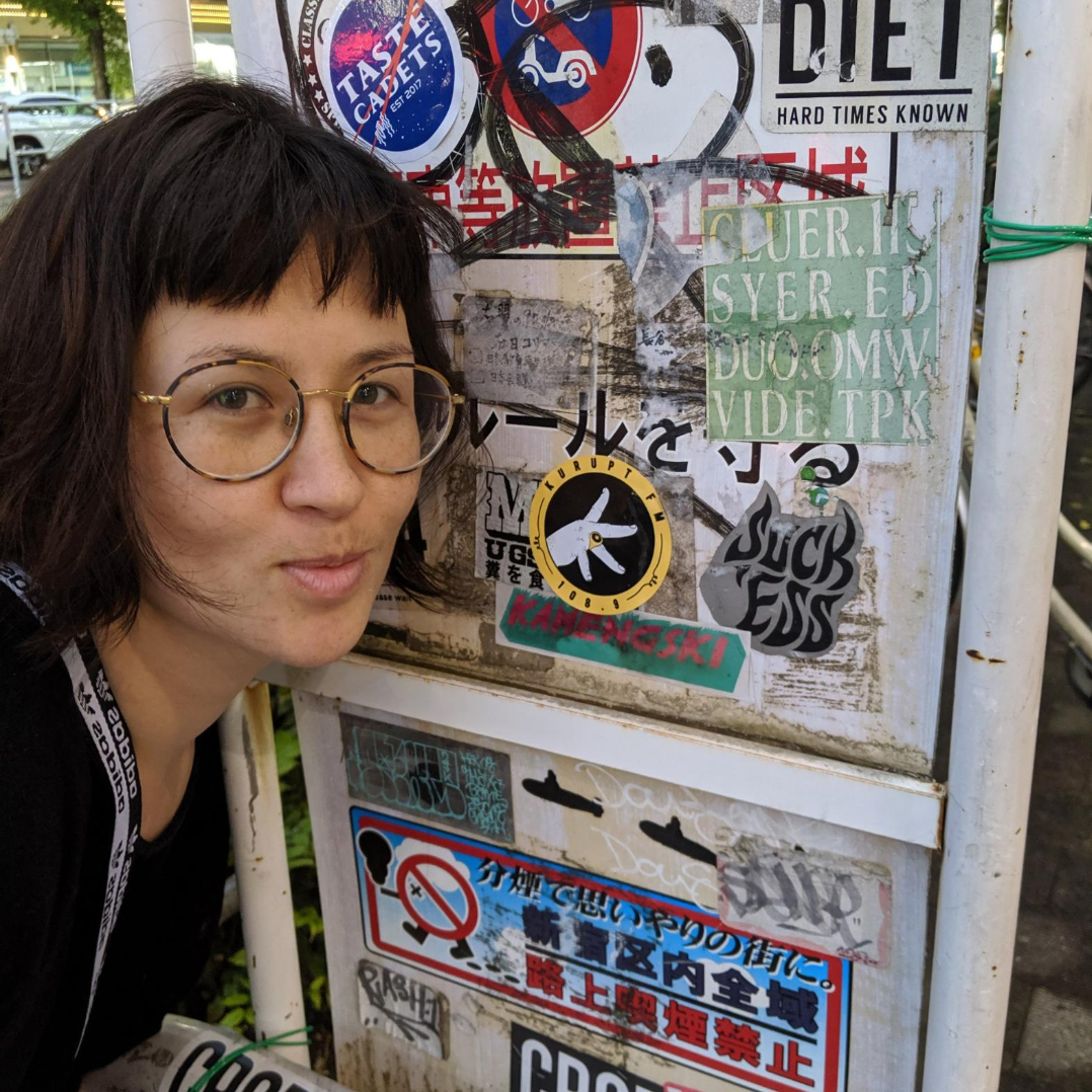 Pamela posing near stickers on a street sign